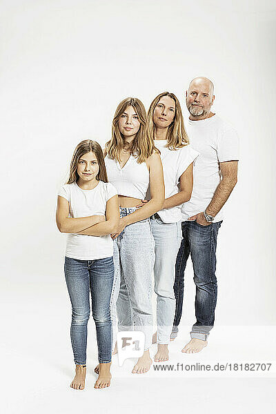 Confident family with two children standing in row at studio