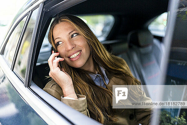 Lächelnde Geschäftsfrau  die im Auto mit dem Handy telefoniert