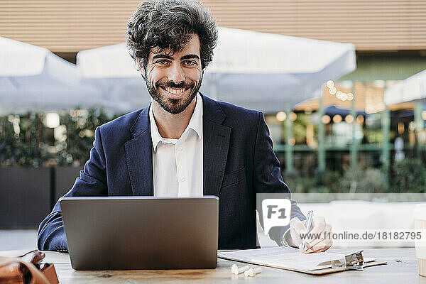 Handsome businessman with document and laptop working in cafe