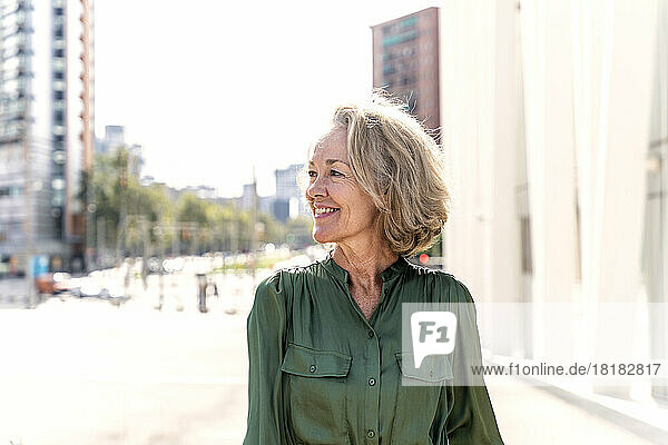Smiling woman with gray hair in city on sunny day