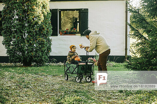 Father talking to son sitting in wagon outside house