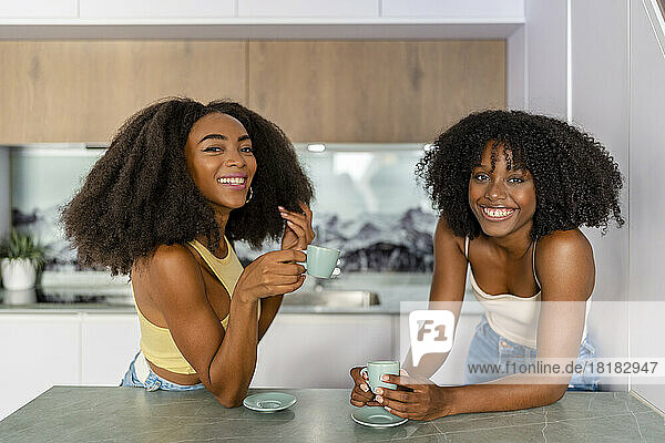 Happy multiracial friends having coffee in kitchen