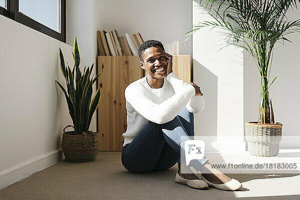 Smiling relaxed woman sitting on the floor at home