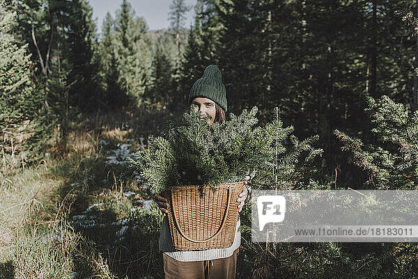 Woman with basket of spruce twigs in forest