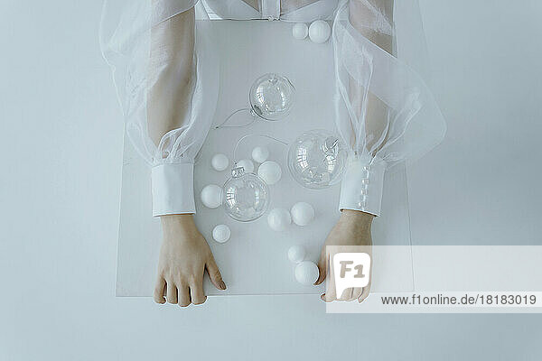 Hands of girl with transparent Christmas balls over white background