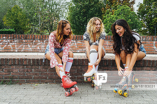 Woman with friends tying lace of roller skates on wall