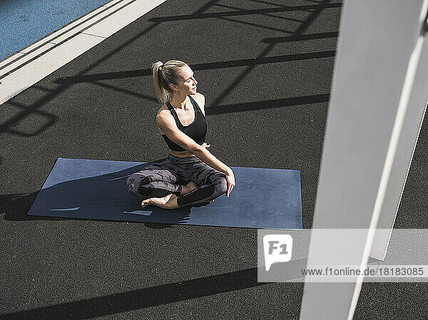 Young sportswoman practicing yoga on exercise mat