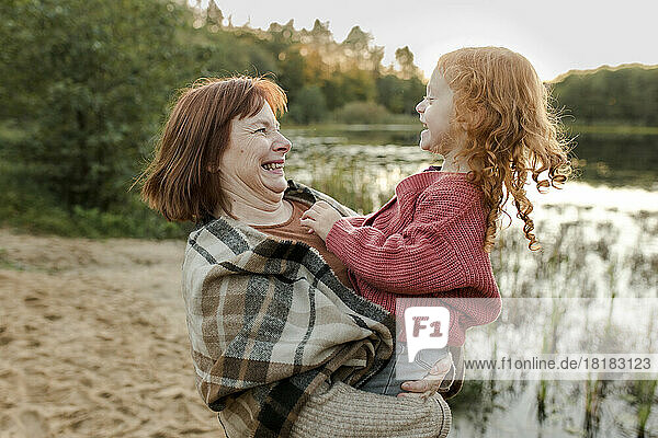 Glückliche Großmutter  die mit Enkelin am See spielt