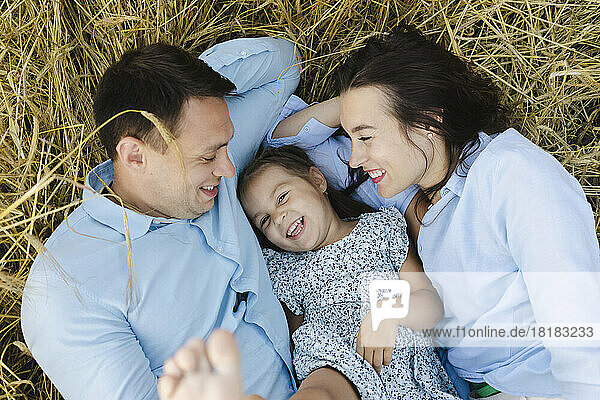 Happy girl lying with father and mother in field