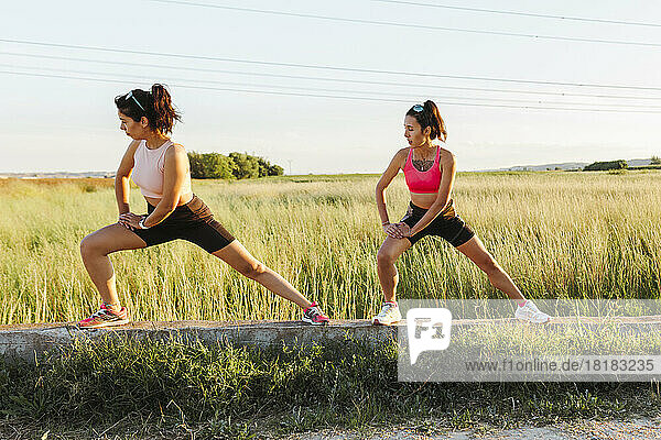 Instructor with woman exercising in front of field