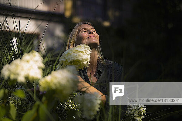 Mature woman with eyes closed enjoying sunshine in garden