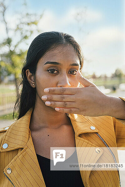 Young woman covering mouth on sunny day