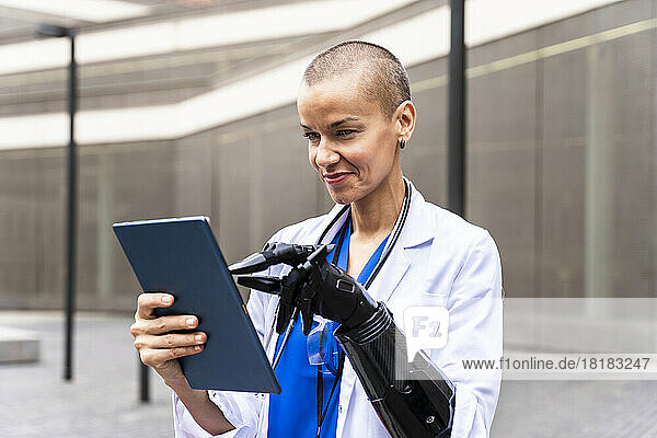 Smiling female doctor using tablet PC with artificial hand