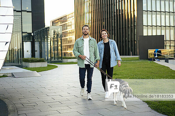 Paar mit Hund läuft auf Fußweg