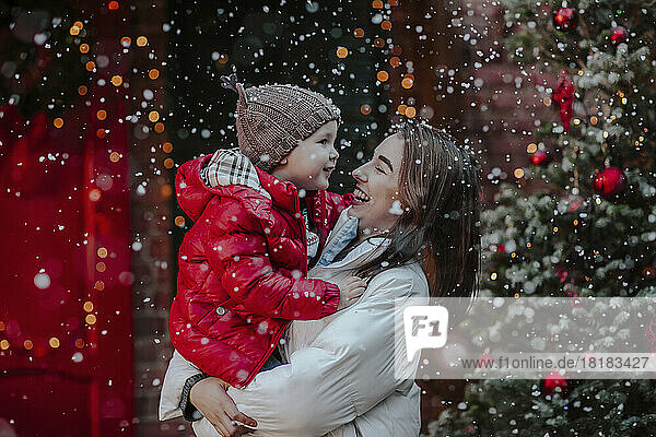 Cheerful woman with son enjoying in snow