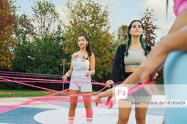Young woman with friend holding pink string at sports court