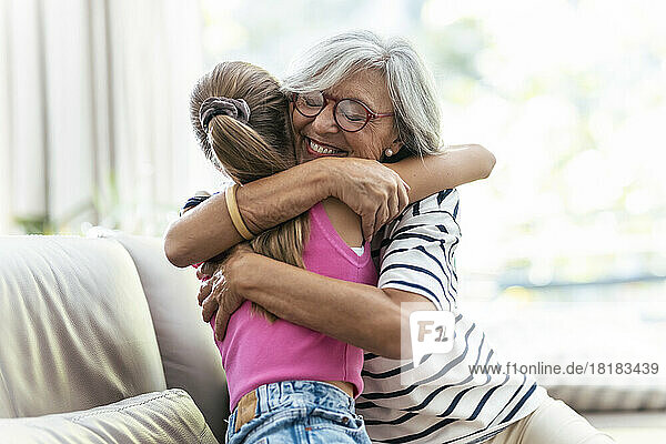 Glückliche Seniorin umarmt Enkelin zu Hause