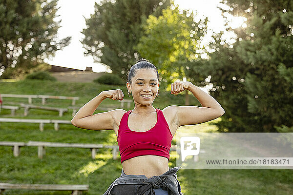 Happy young woman flexing muscles in park
