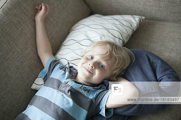 Smiling little boy lying on couch