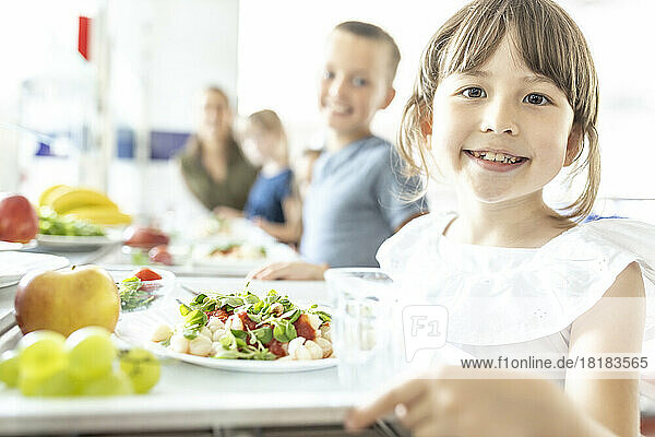 Smiling student with healthy lunch at school cafeteria