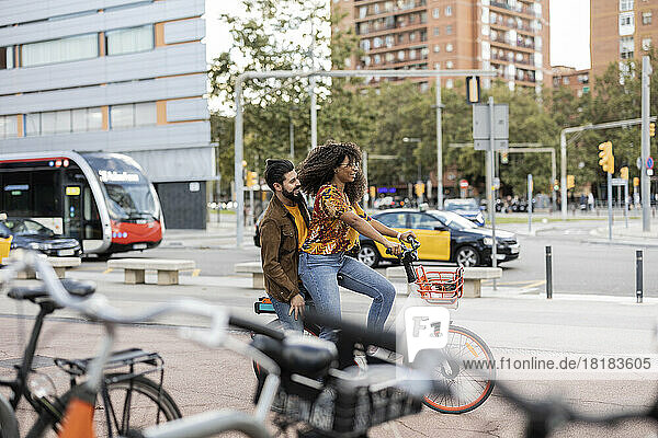 Junger Mann sitzt mit Freundin auf dem Fahrrad am Fußweg