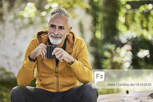 Thoughtful mature man sitting with coffee cup in park