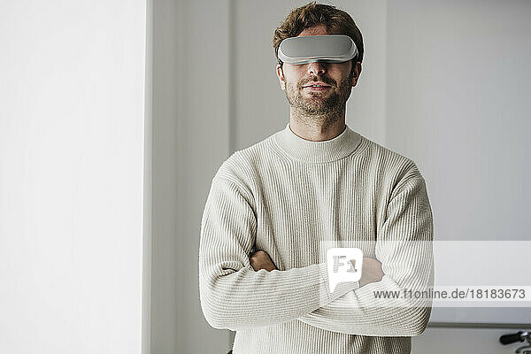 Businessman with arms crossed wearing futuristic goggles