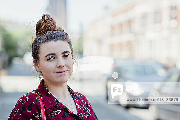 Portrait of smiling woman with bun in the city