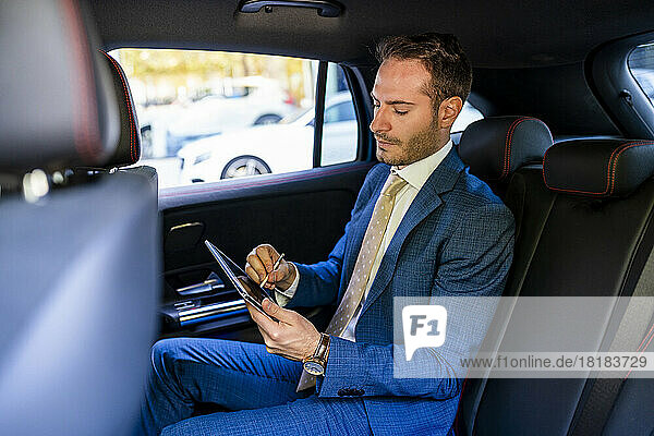 Businessman using tablet PC sitting in taxi