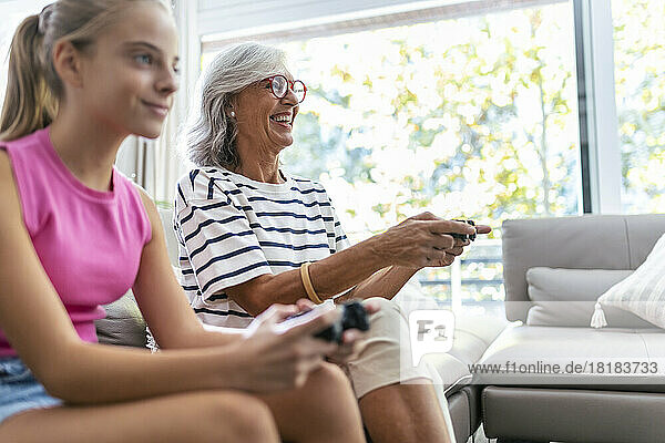 Glückliche Großmutter spielt zu Hause Videospiel mit Enkelin