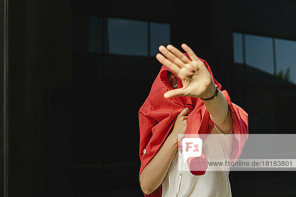 Geschäftsfrau im roten Blazer gestikuliert an einem sonnigen Tag mit einem Stoppschild