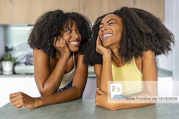 Cheerful Afro lesbian couple leaning on elbows at home