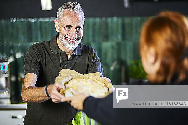 Smiling man handing over savory pie