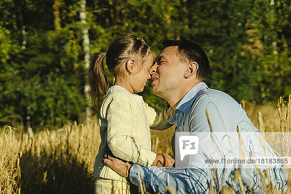 Father embracing daughter in field