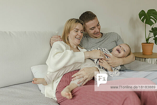 Happy mother and father enjoying with son on sofa at home