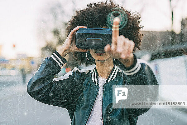 Young woman with afro hairstyle wearing VR glasses in front of transparent screen