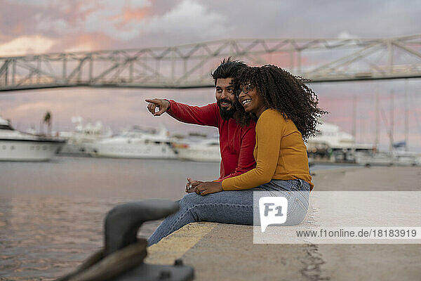 Happy woman with boyfriend gesturing at harbor