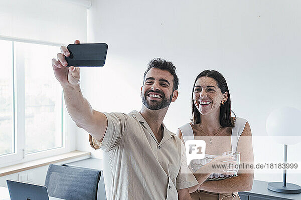 Happy business people talking selfie through smart phone in office