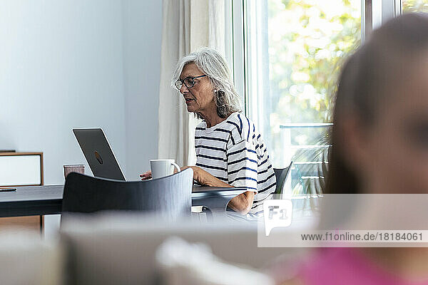 Senior woman using laptop at table in home