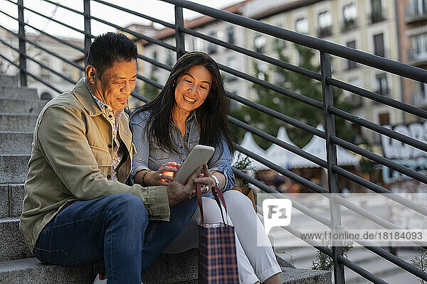 Lächelndes älteres Paar mit Tablet-PC auf Stufen sitzend