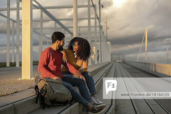 Smiling woman with man sitting on steps at sunset