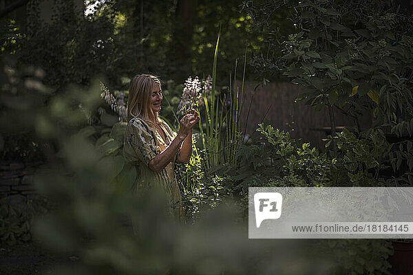 Smiling woman looking at plant in garden