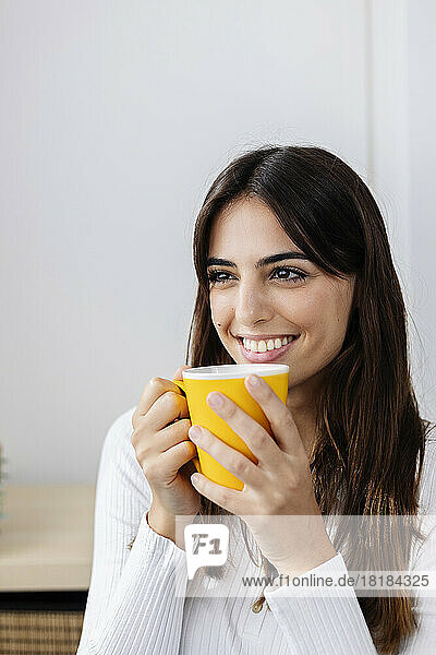 Smiling woman holding coffee cup at home
