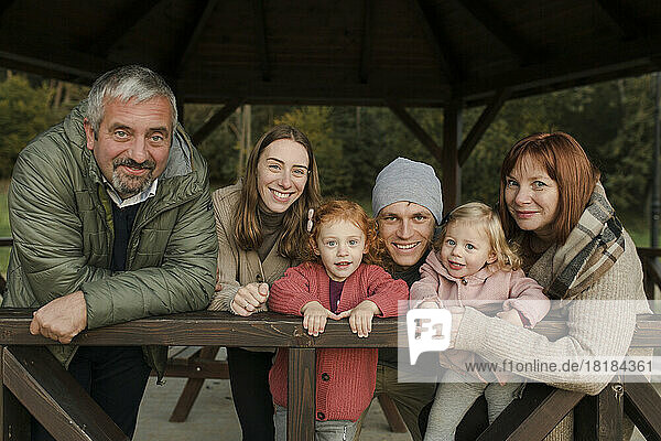 Happy family in warm clothing leaning on railing