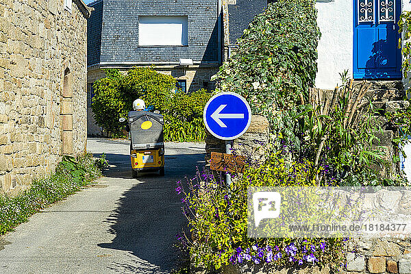Frankreich  Bretagne  Saint-Pierre-Quiberon  Straßenschild vor der Stadtgasse mit fahrendem Elektroauto im Hintergrund