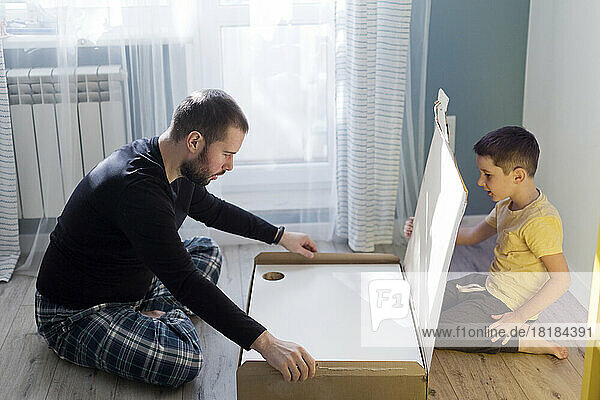 Vater und Sohn bauen zu Hause den Tisch zusammen