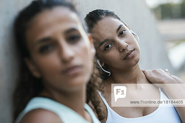 Teenage girl with friend leaning on wall
