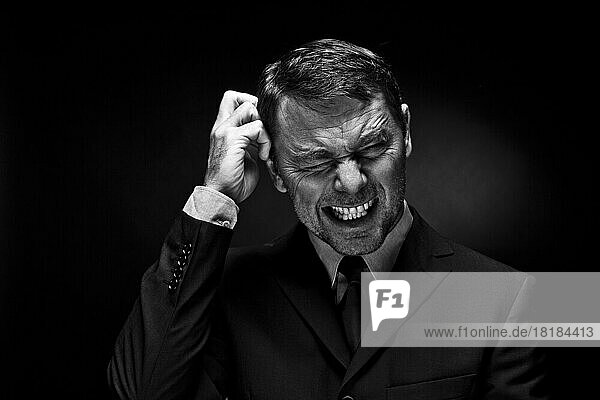 Mature man clenching teeth against black background