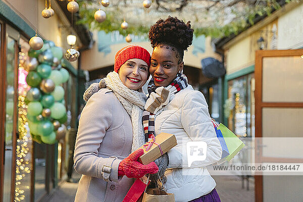 Smiling women wearing warm clothing holding gifts on Christmas festival