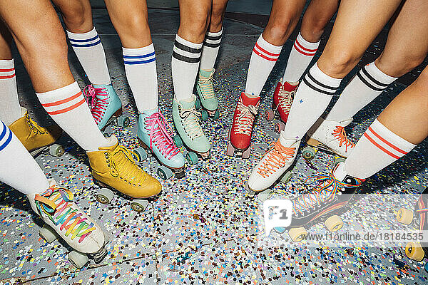 Legs of women wearing roller skates over confetti